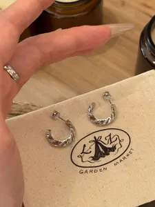 Close-up of twisted zircon hoop earrings on a natural fabric jewelry pouch.