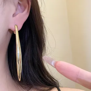Close-up detail of minimalist gold water drop dangle earrings worn by a model
