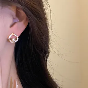 Primo piano di un elegante orecchino a cerchio geometrico con perla e strass.