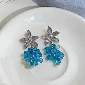 Detalle de pendientes de estrella de mar con colgantes de uvas de cuentas azules en plato