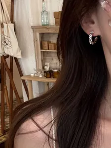 Detailed view of an elegant silver twisted hoop earring with sparkling zircons worn by model