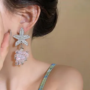 Detalle de elegantes pendientes de estrella de mar con colgantes de uvas rosas