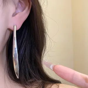 Detailed close-up showing a stylish silver metallic drop pendant earring worn on an ear