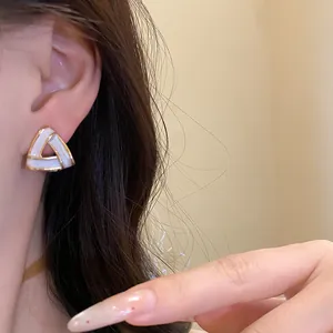 Vista dettagliata di un orecchino geometrico a triangolo indossato su orecchio donna