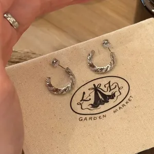 Detailed view of silver-toned twist hoop earrings featuring sparkling cubic zirconia stones.