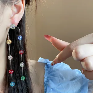 Detailed view of exquisite multi-colored glass bead tassel earrings worn by a fashion model.