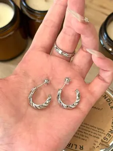 Close-up of twisted silver hoop earrings with pave cubic zirconia stones