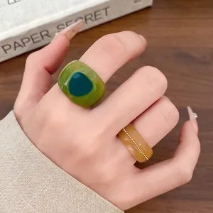 Detailed view of two minimalist resin rings with marbled texture and golden bead accents