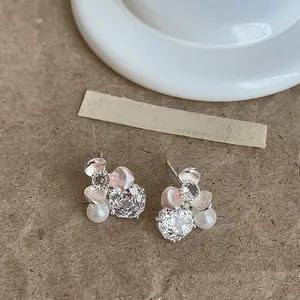 Macro detail of flower-shaped stud earrings with clear zircons and white pearls