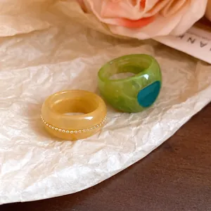 Detail view of resin marbled ring set in amber and green with elegant textures