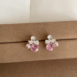 Macro detail of elegant pink flower stud earrings with pearls and sparkly zircon