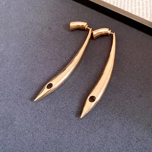 Detailed close-up of minimalist gold long drop earrings with unique curved design.