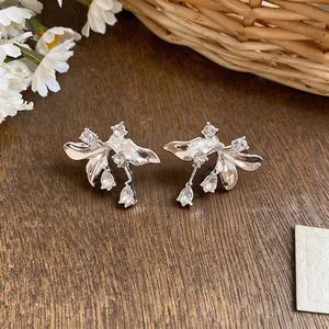 Elegant French-style silver flower earrings with clear crystal drops on rustic wood