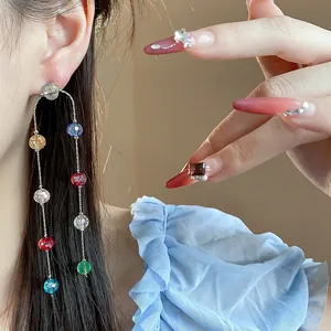 Detailed view of colorful glass bead tassel earrings and matching brown stone ring