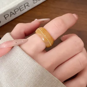 Detailed view of a stylish amber-colored marbled resin ring with gold bead chain inlay