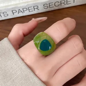 Macro shot of a chunky resin ring featuring a vibrant green marble effect worn on a finger