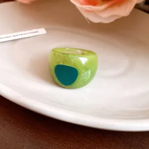 Detailed macro shot of a green marbled resin ring on a white ceramic plate