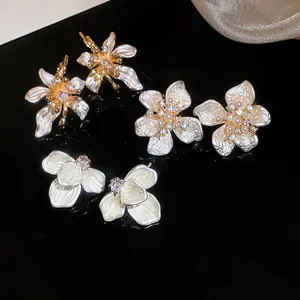 Macro detail view of elegant French-style floral earrings with zircon and white enamel