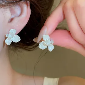 Close-up detail of elegant white oil-drop flower earrings with zircon center on ear