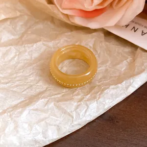 Detail view of a thick amber resin ring featuring a delicate gold beaded center line.
