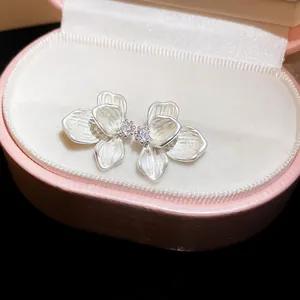 Detailed view of white enamel flower earrings with zircon center in a pink box