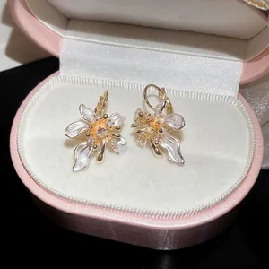 Close-up of pearl white enamel flower earrings with sparkling zircon centers in pink box