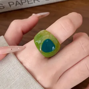 Detailed view of a chunky green resin marbled ring on a finger.