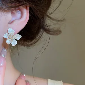 Macro view of elegant white enamel flower earring featuring pearl and zircon center details
