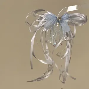 Exquisite detail of a light blue ribbon bow hair clip with pearls and delicate charms.