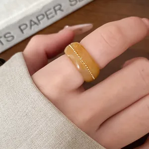 Close-up view of elegant amber marbled resin ring featuring a delicate gold bead line detail.