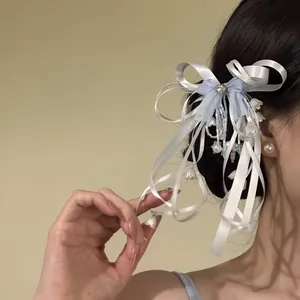 Detail view of a blue bow ribbon hair clip with delicate pearl and flower beads