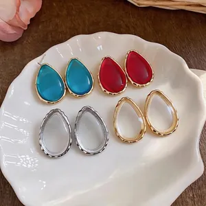 Minimalist waterdrop resin stud earrings in multiple vibrant colors on decorative shell plate
