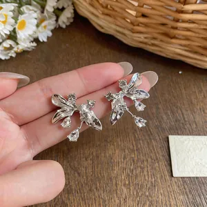 Detail view of silver floral earrings with sparkling crystals held in hand.