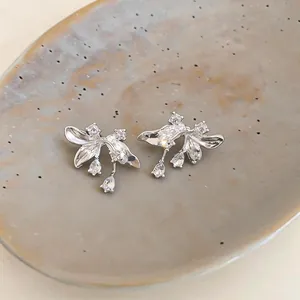 Close-up of elegant silver flower stud earrings with sparkling stones on a ceramic plate