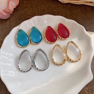 Detail view of minimalist teardrop resin earrings in multiple colors on a shell plate