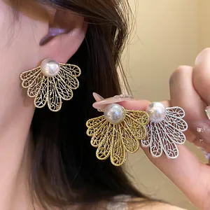 Detailed view of vintage filigree leaf earrings with pearl in gold and silver colors