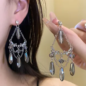 Vue détaillée de boucles d'oreilles argentées avec pompons en cristal gris