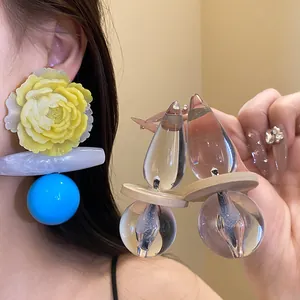 Close-up of exaggerated retro resin flower earrings with blue bead and glass drops