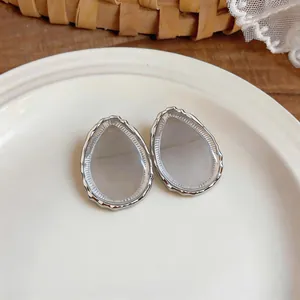 Macro detail of teardrop resin stud earrings with textured silver-tone metal frame
