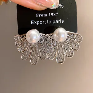 Detail shot of vintage hollow leaf stud earrings with white pearl center.