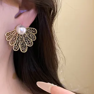 Elegant close-up of vintage hollow leaf gold earrings featuring a pearl stud detail