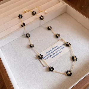 Elegante collana vintage a catena dorata con ciondoli a forma di piccoli fiori neri