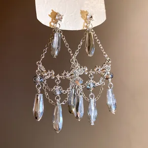 Gros plan de boucles d'oreilles à pompons argentés avec cristaux en forme de larme gris.