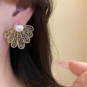 Close-up detail of vintage golden hollow leaf stud earring with a white pearl worn on the ear