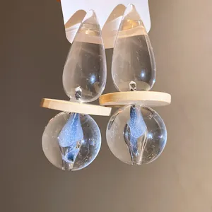 Artistic clear resin drop earrings featuring teardrop shape and blue swirl detail