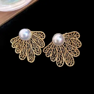 Detailed macro view of vintage gold hollowed leaf stud earrings featuring elegant white pearls