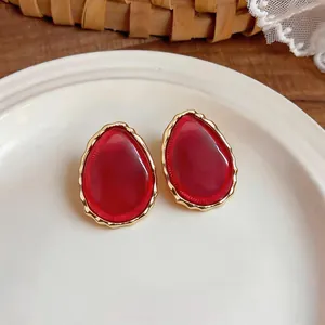 Detail view of red teardrop resin earrings with gold scalloped borders
