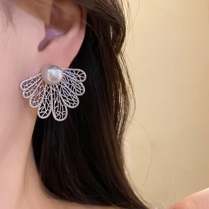 Detail shot of vintage hollow silver fan earrings with elegant gray pearl on model's ear