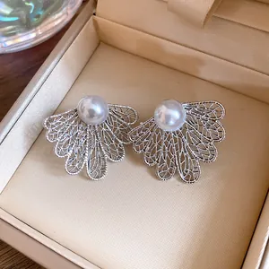Detailed view of elegant silver openwork leaf earrings with white pearls in jewelry box