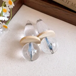 Detailed view of clear resin pendant earrings with wooden discs and blue glitter